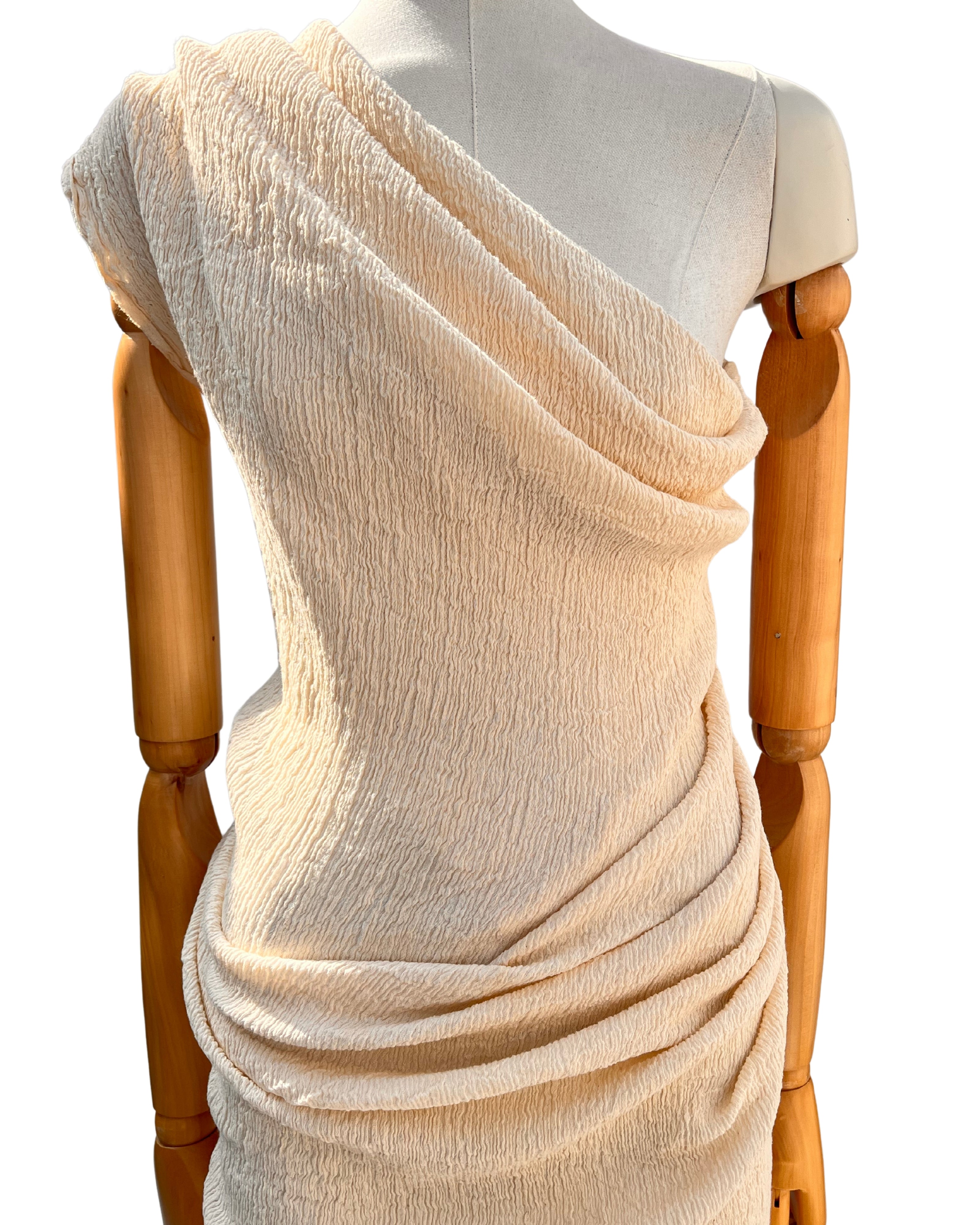 Tissu en coton froissé extensible neutre, surface texturée, coton tissé à la main blanc cassé, coton beige biologique semi-transparent et non blanchi.
