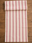 A folded piece of cream-colored fabric with vertical red stripes, laid flat on a rustic wooden surface.