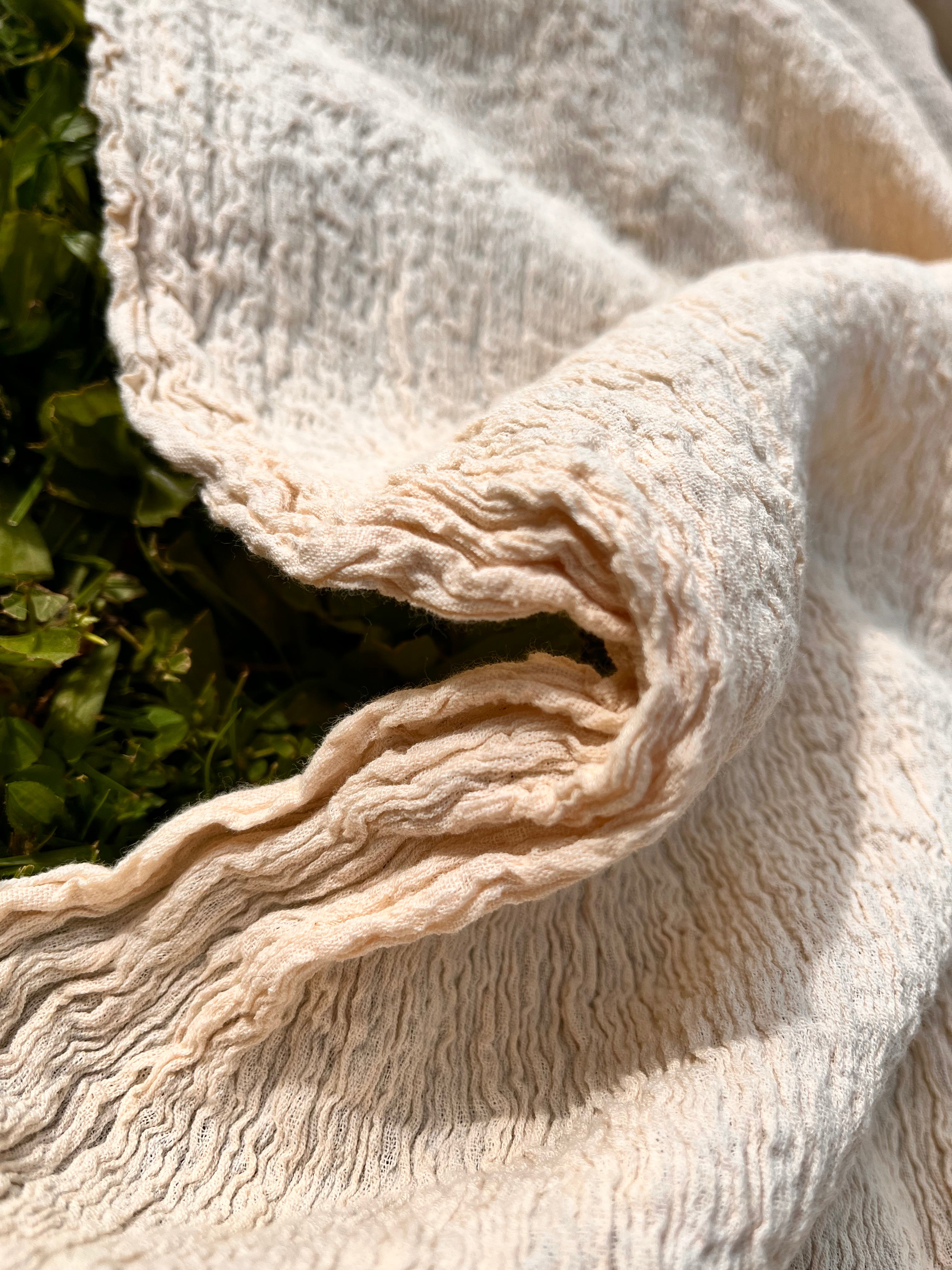 Tissu en coton froissé extensible neutre, surface texturée, coton tissé à la main blanc cassé, coton beige biologique semi-transparent et non blanchi.