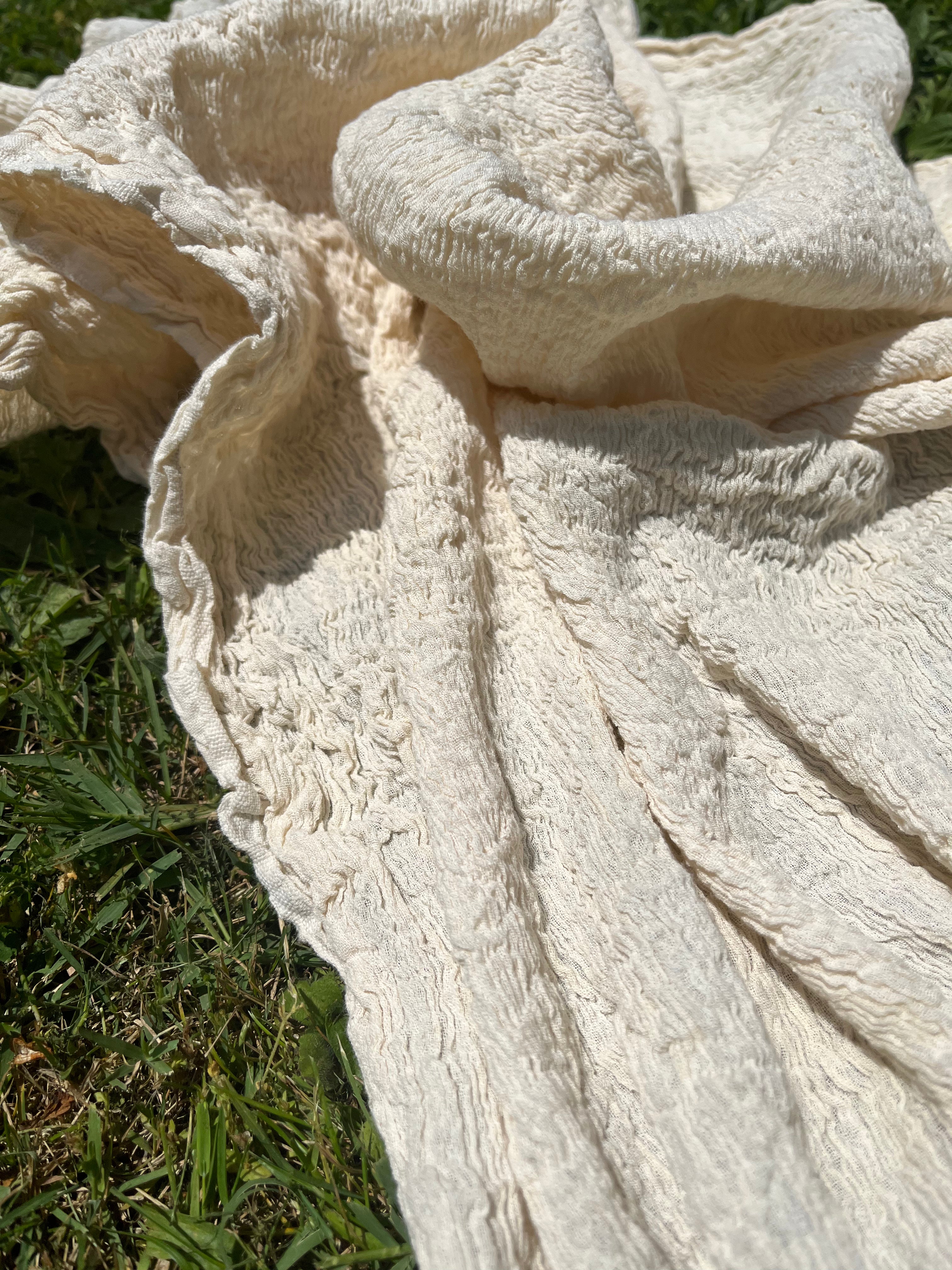 Tissu en coton froissé extensible neutre, surface texturée, coton tissé à la main blanc cassé, coton beige biologique semi-transparent et non blanchi.