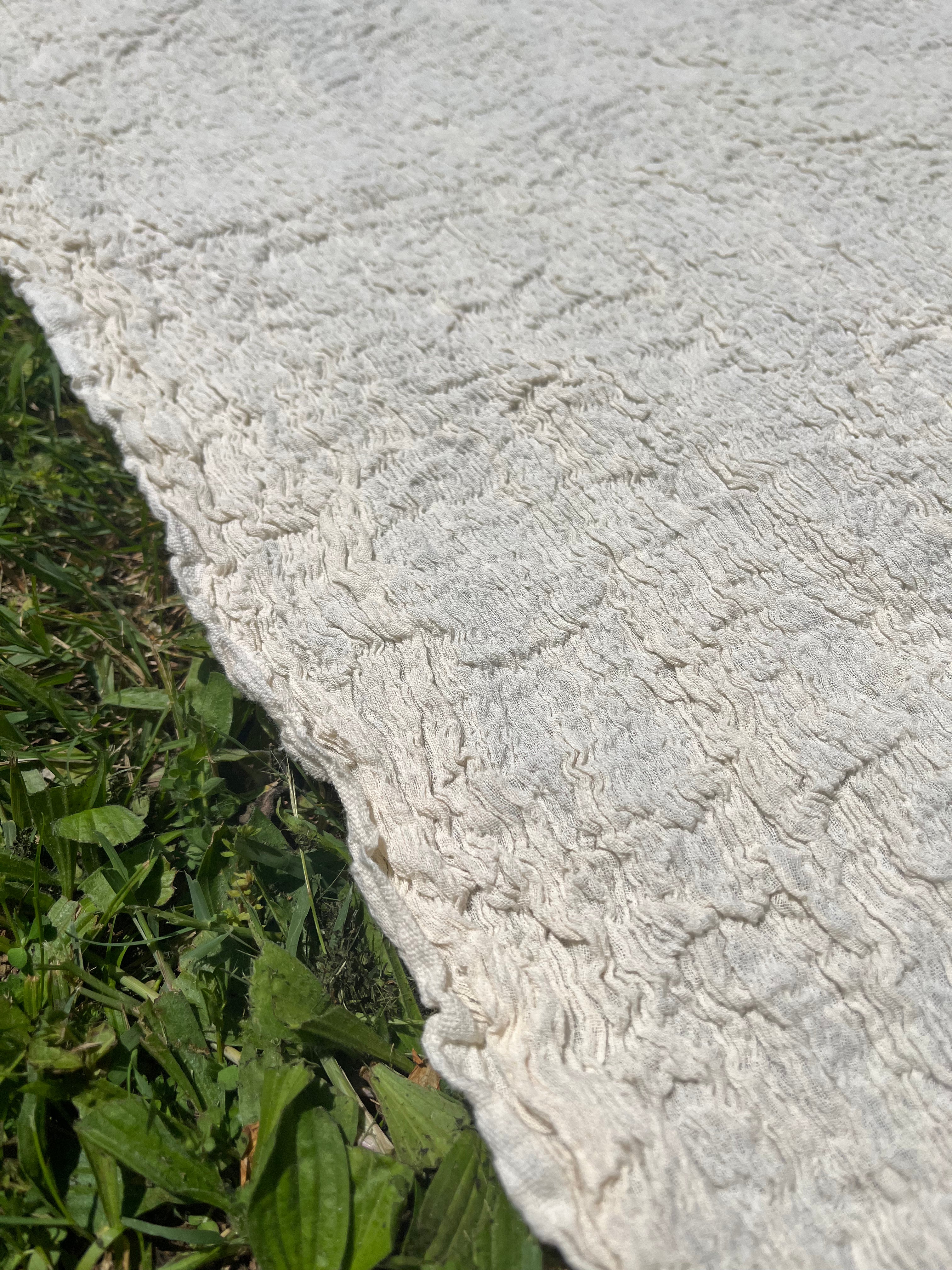 Tissu en coton froissé extensible neutre, surface texturée, coton tissé à la main blanc cassé, coton beige biologique semi-transparent et non blanchi.
