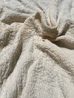 Tissu en coton froissé extensible neutre, surface texturée, coton tissé à la main blanc cassé, coton beige biologique semi-transparent et non blanchi.