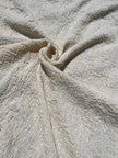 Tissu en coton froissé extensible neutre, surface texturée, coton tissé à la main blanc cassé, coton beige biologique semi-transparent et non blanchi.