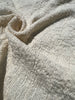 Tissu en coton froissé extensible neutre, surface texturée, coton tissé à la main blanc cassé, coton beige biologique semi-transparent et non blanchi.