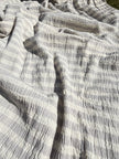 Tissu en coton froissé extensible neutre, surface texturée, coton tissé à la main blanc cassé, coton beige biologique semi-transparent et non blanchi.