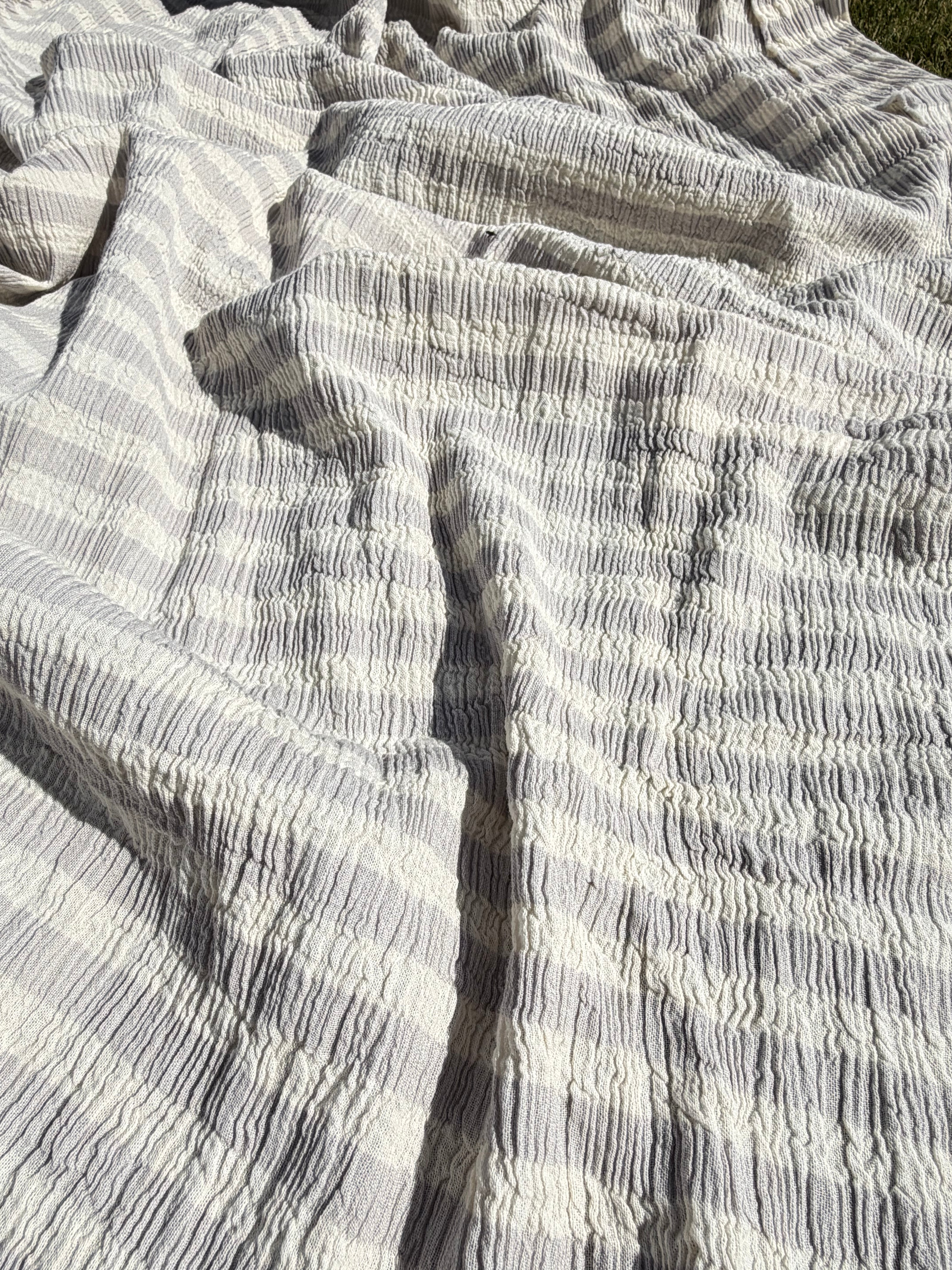 Tissu en coton froissé extensible neutre, surface texturée, coton tissé à la main blanc cassé, coton beige biologique semi-transparent et non blanchi.