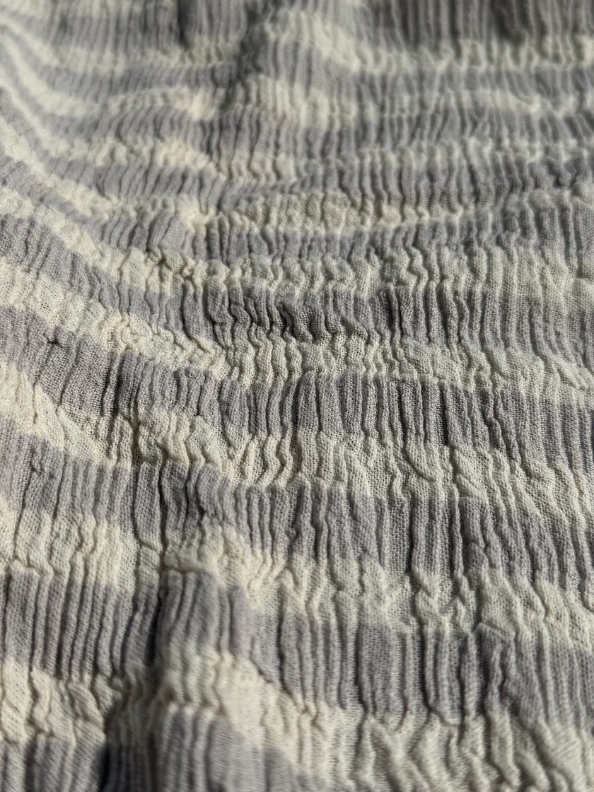 Tissu en coton froissé extensible neutre, surface texturée, coton tissé à la main blanc cassé, coton beige biologique semi-transparent et non blanchi.