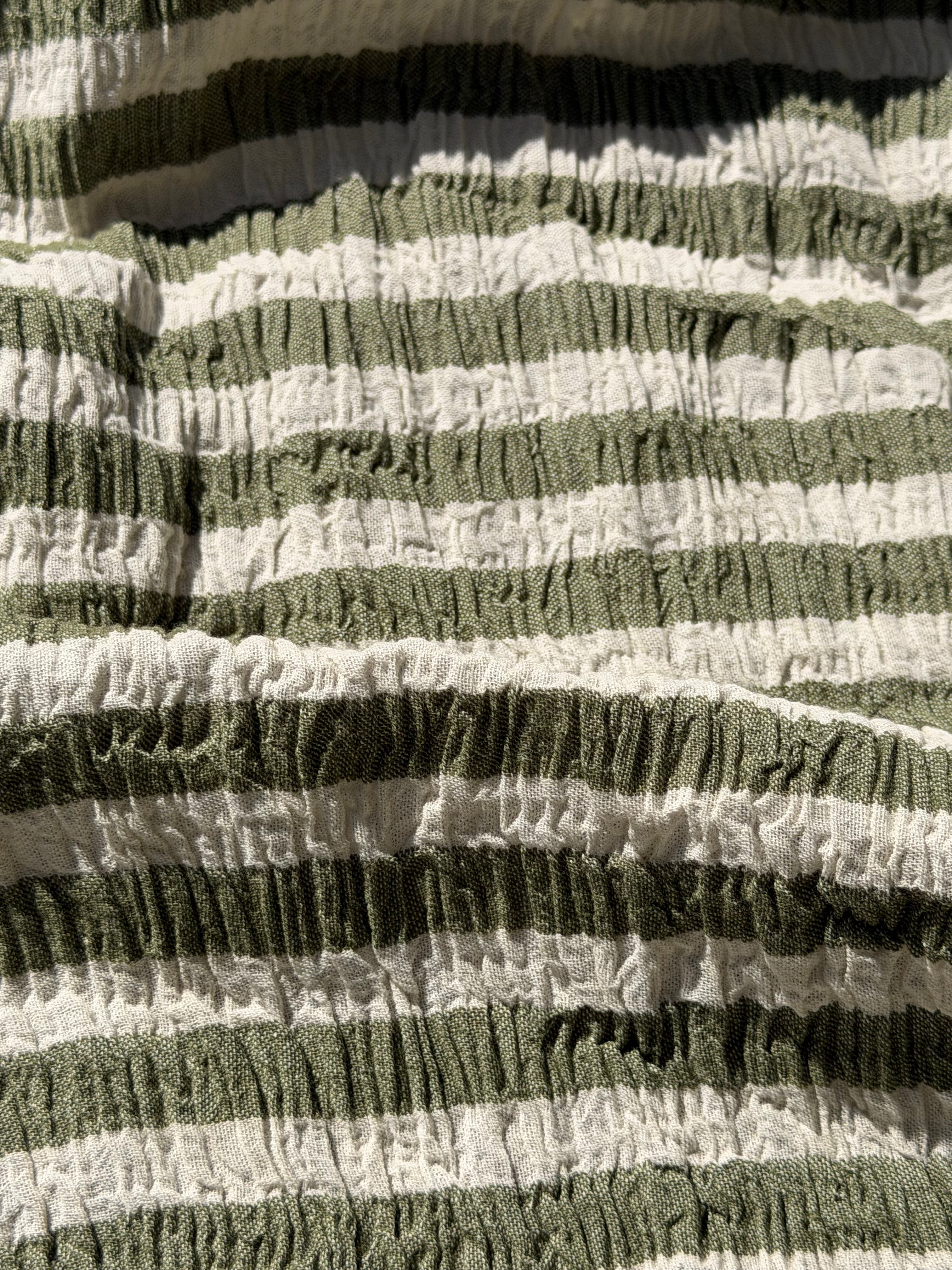 Tissu en coton froissé extensible neutre, surface texturée, coton tissé à la main blanc cassé, coton beige biologique semi-transparent et non blanchi.