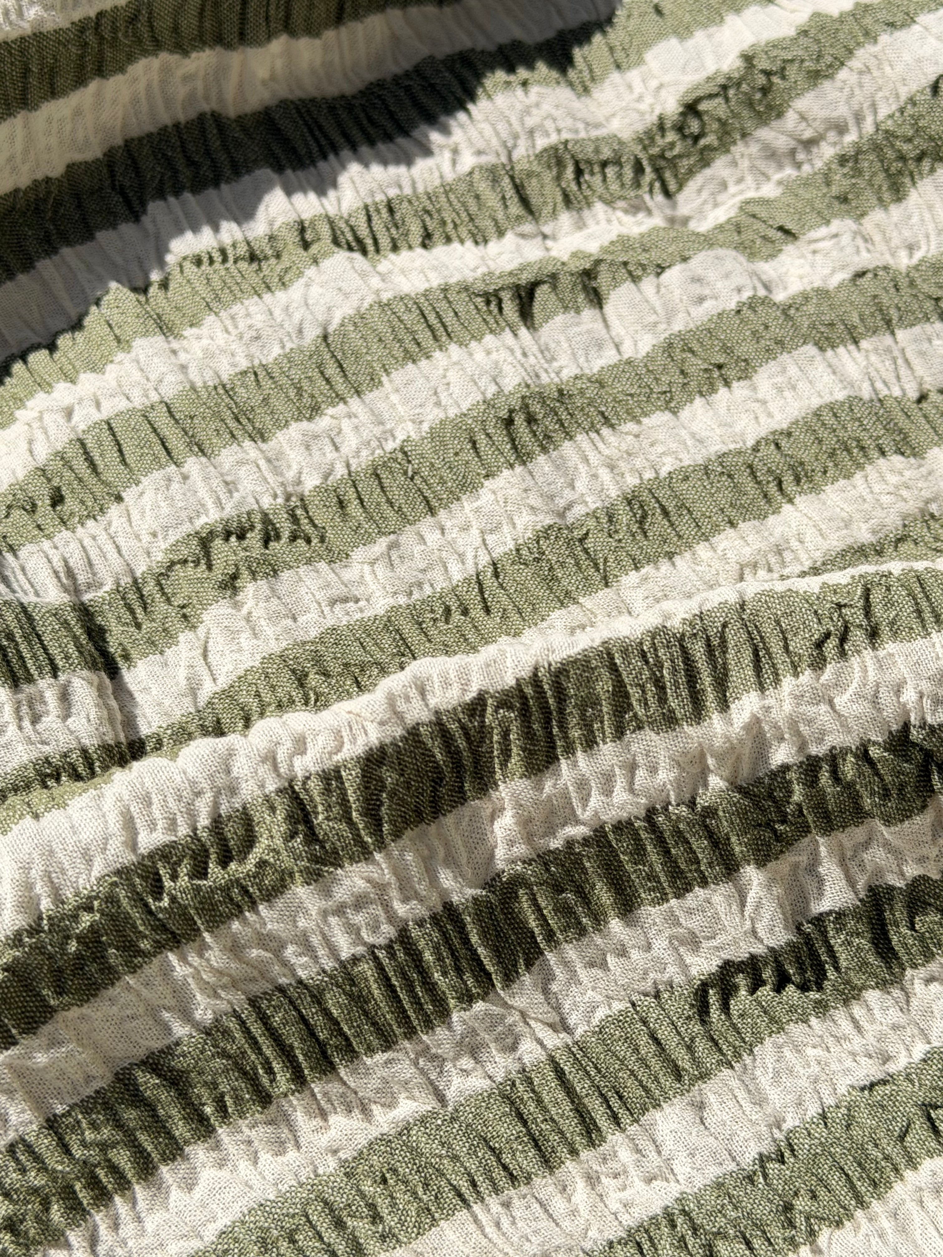 Tissu en coton froissé extensible neutre, surface texturée, coton tissé à la main blanc cassé, coton beige biologique semi-transparent et non blanchi.
