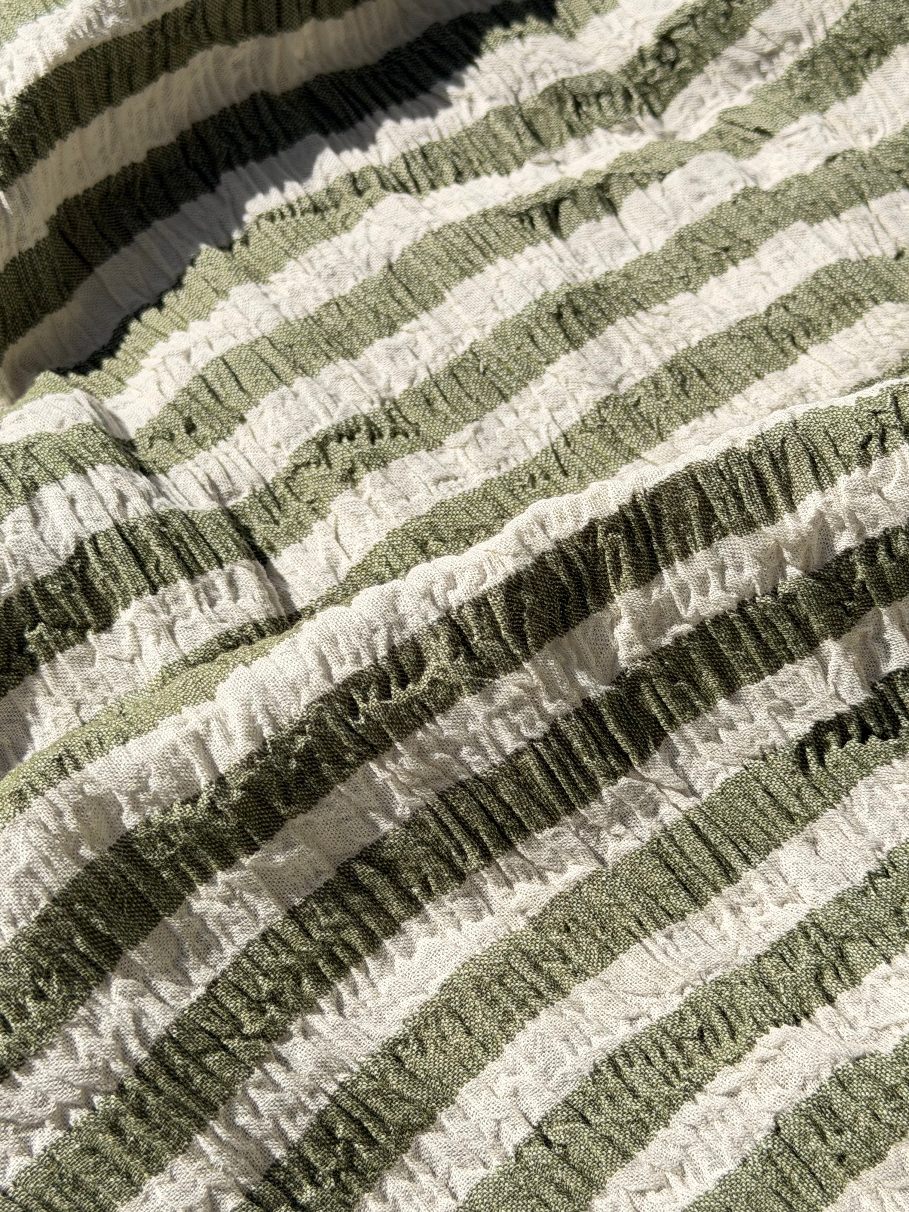 Tissu en coton froissé extensible neutre, surface texturée, coton tissé à la main blanc cassé, coton beige biologique semi-transparent et non blanchi.