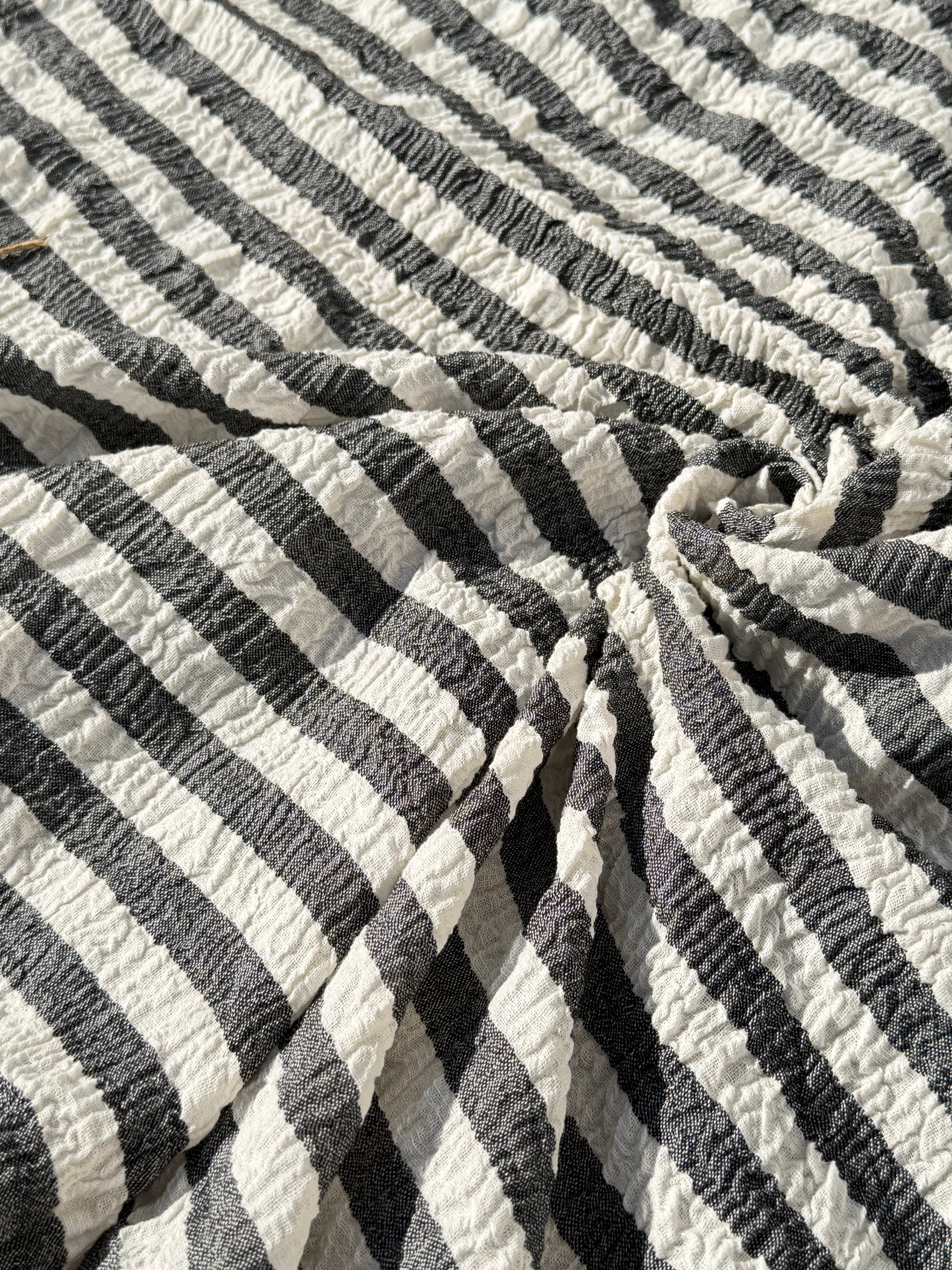 Tissu en coton froissé extensible neutre, surface texturée, coton tissé à la main blanc cassé, coton beige biologique semi-transparent et non blanchi.