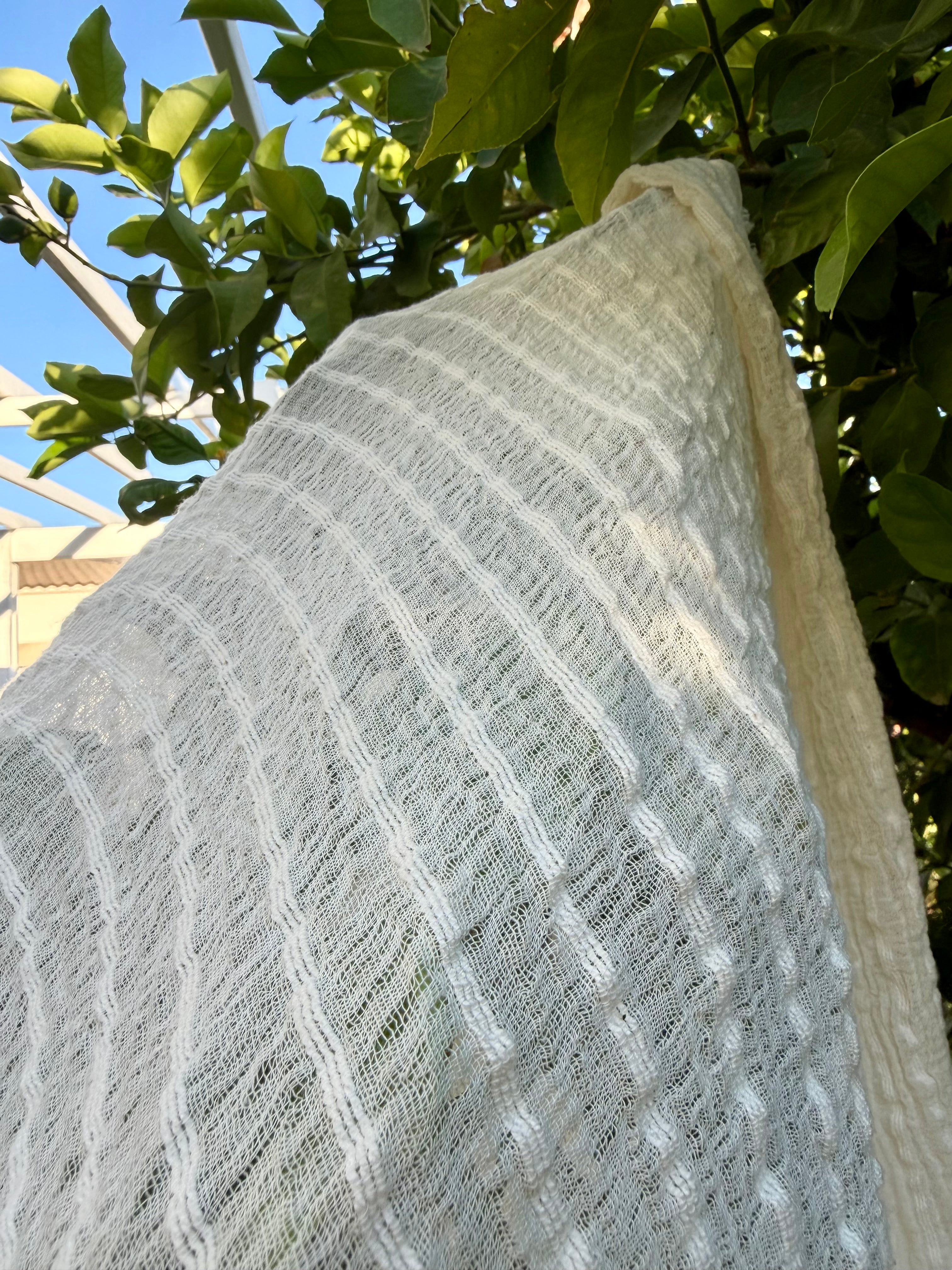 Tissu en coton froissé extensible neutre, surface texturée, coton tissé à la main blanc cassé, coton beige biologique semi-transparent et non blanchi.