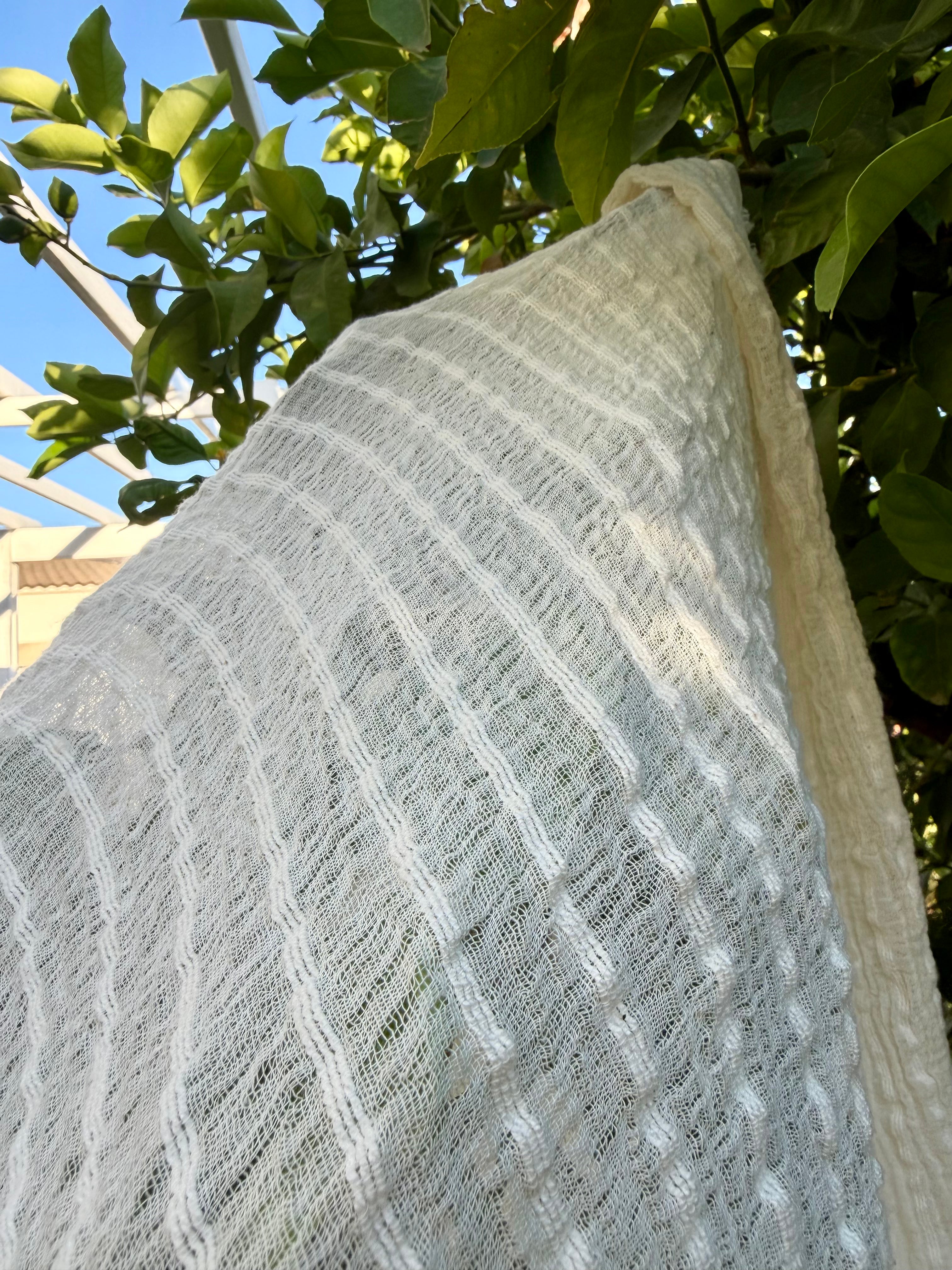 Tissu en coton froissé extensible neutre, surface texturée, coton tissé à la main blanc cassé, coton beige biologique semi-transparent et non blanchi.