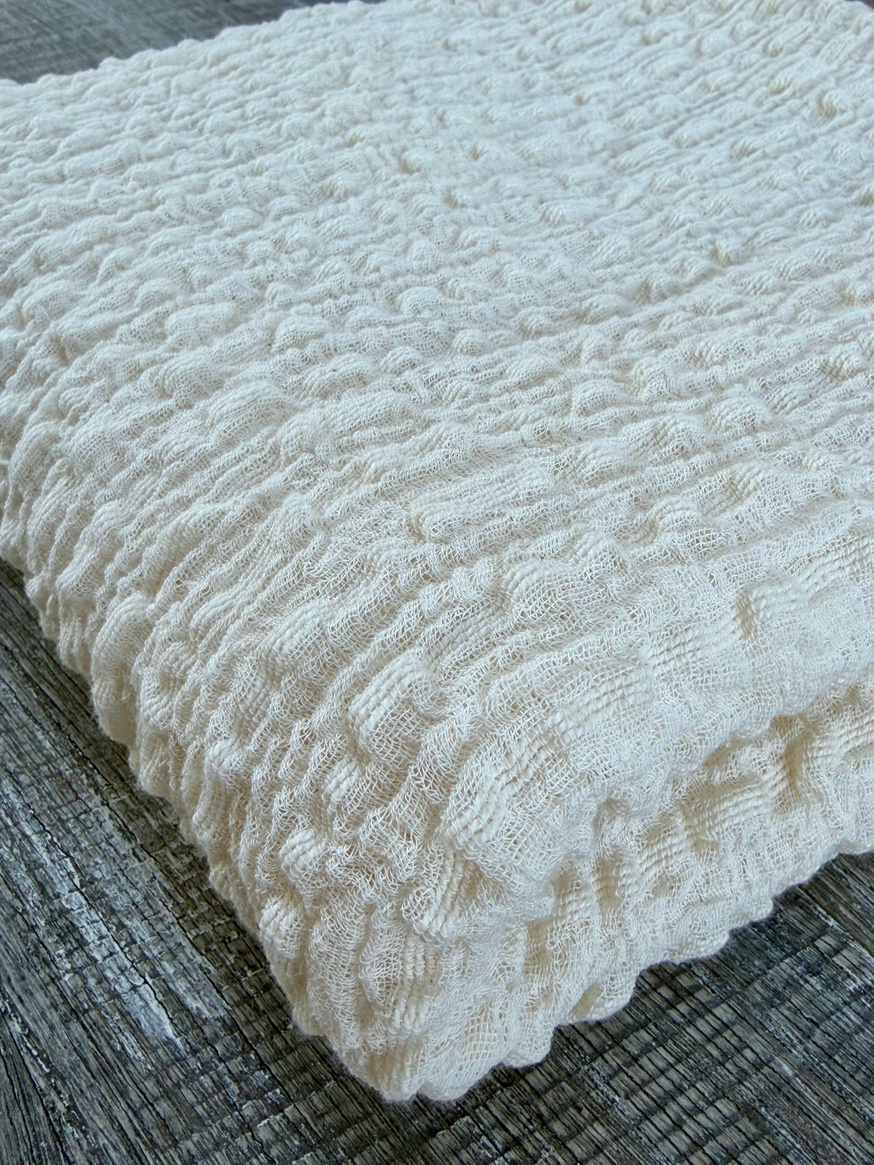 Tissu en coton froissé extensible neutre, surface texturée, coton tissé à la main blanc cassé, coton beige biologique semi-transparent et non blanchi.