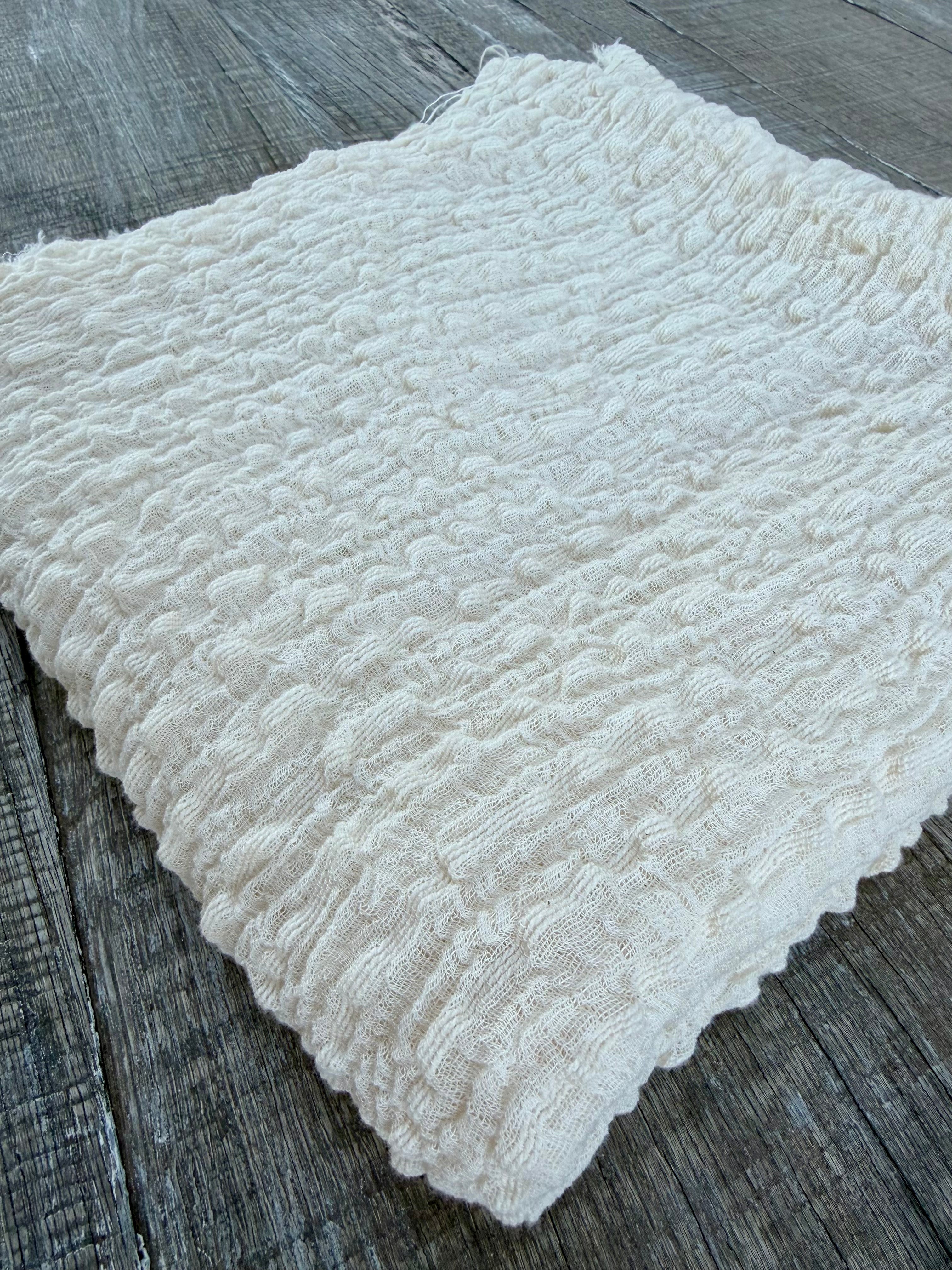 Tissu en coton froissé extensible neutre, surface texturée, coton tissé à la main blanc cassé, coton beige biologique semi-transparent et non blanchi.