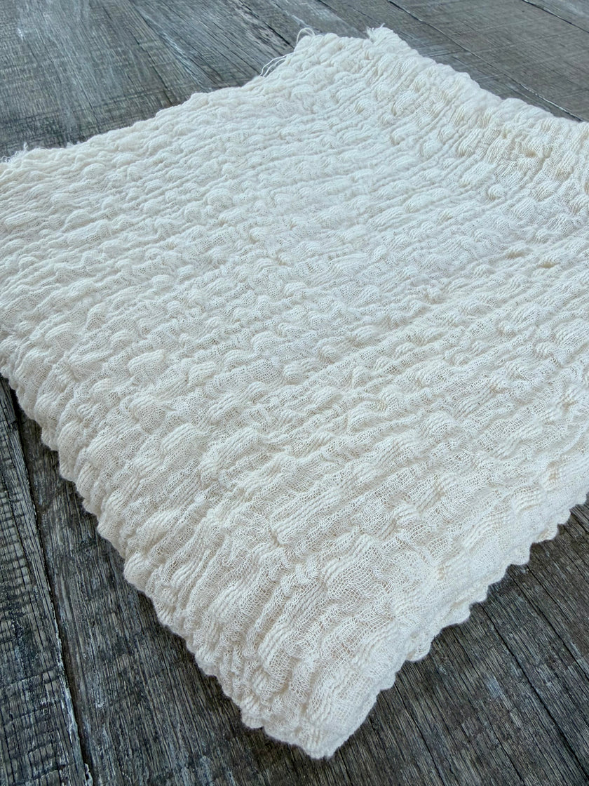 Tissu en coton froissé extensible neutre, surface texturée, coton tissé à la main blanc cassé, coton beige biologique semi-transparent et non blanchi.