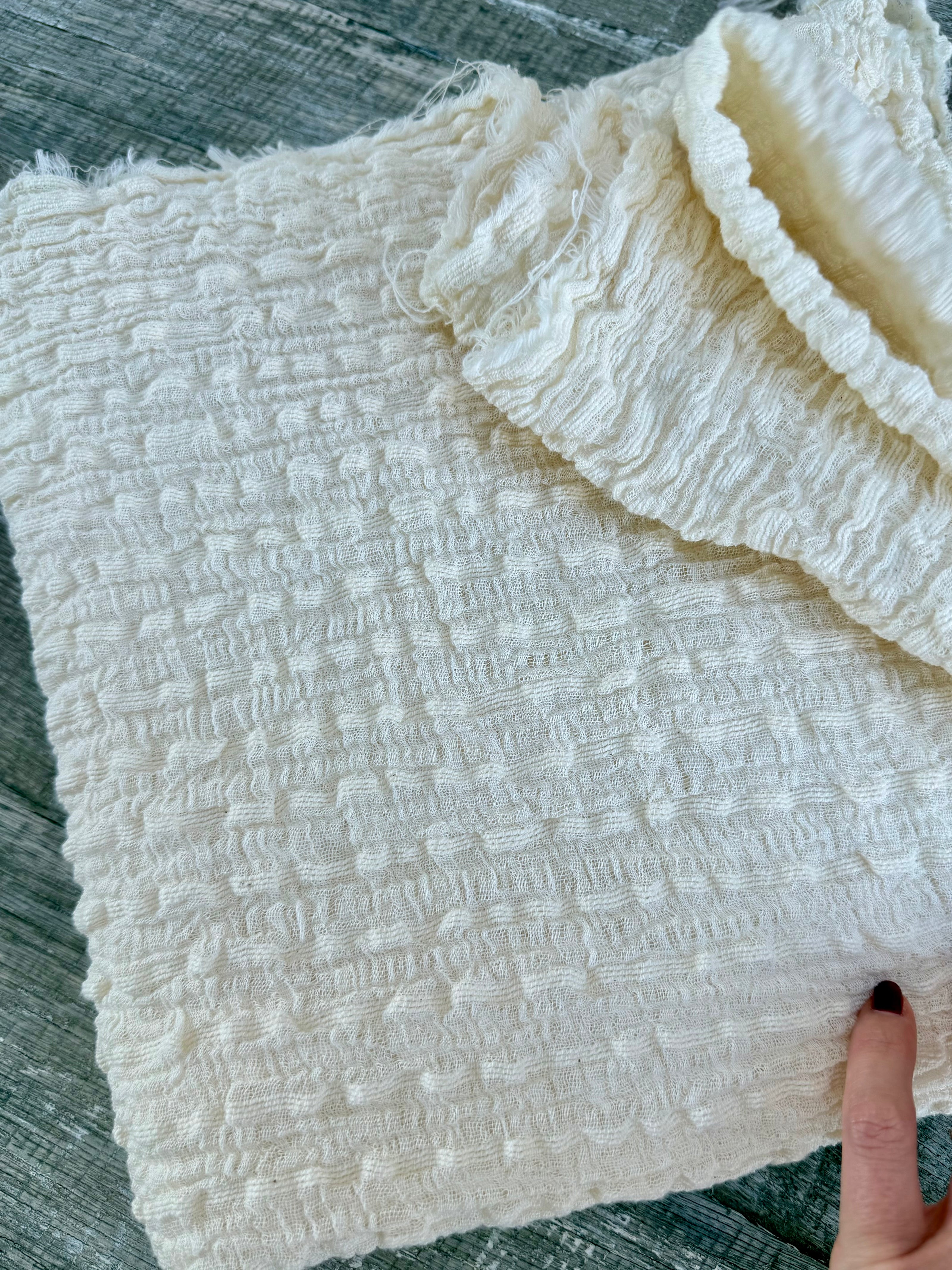 Tissu en coton froissé extensible neutre, surface texturée, coton tissé à la main blanc cassé, coton beige biologique semi-transparent et non blanchi.