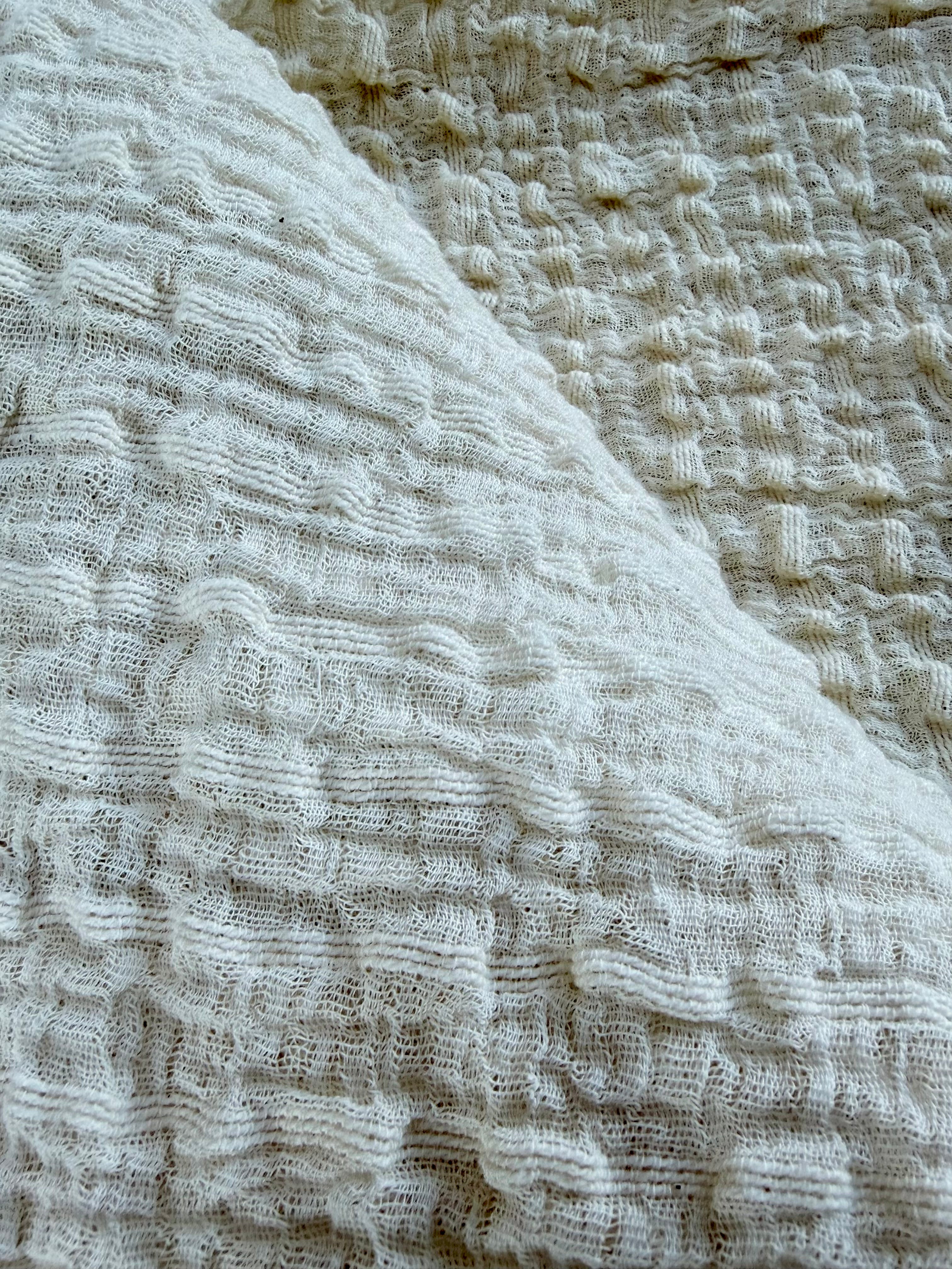 Tissu en coton froissé extensible neutre, surface texturée, coton tissé à la main blanc cassé, coton beige biologique semi-transparent et non blanchi.