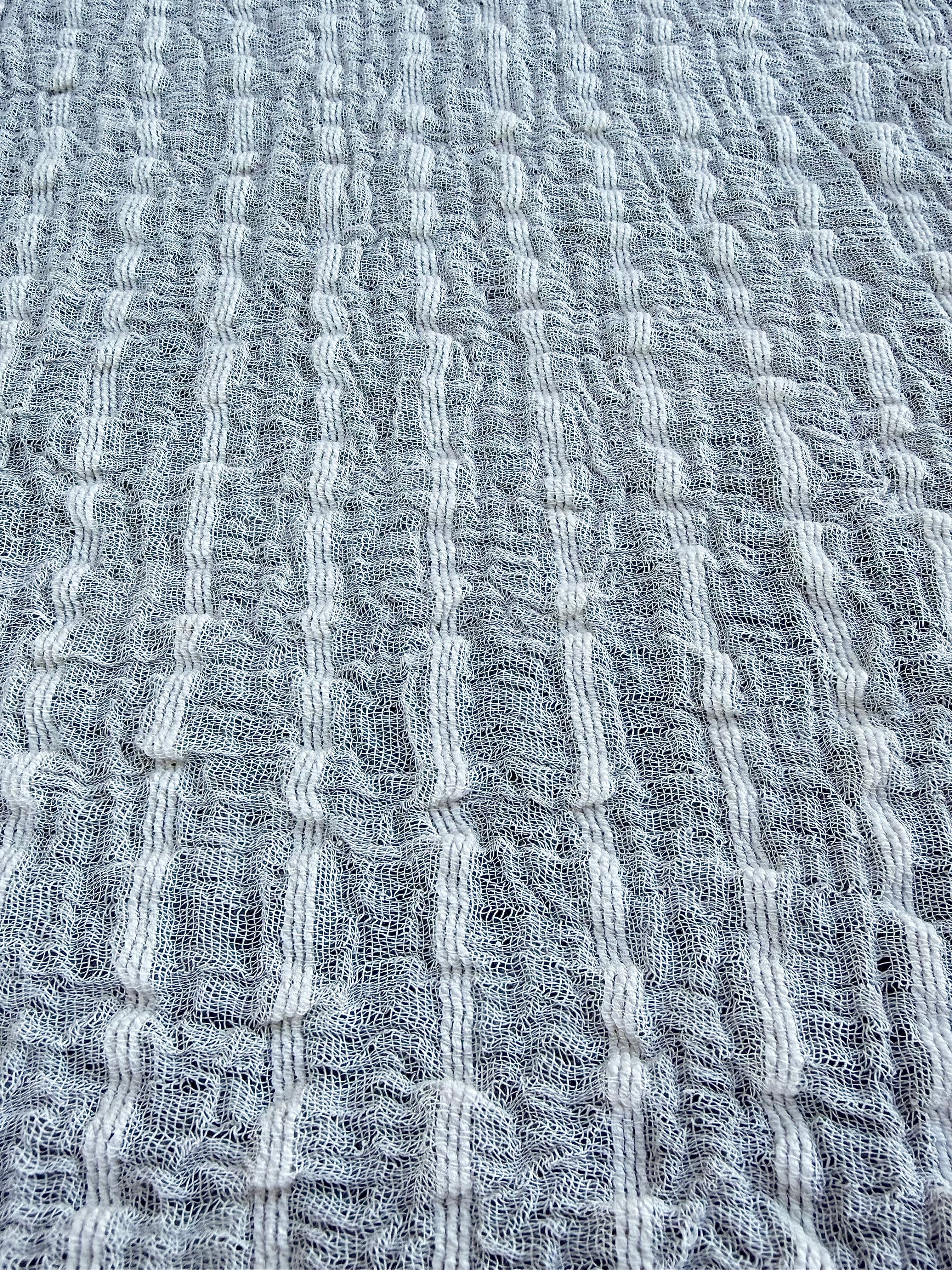 Tissu en coton froissé extensible neutre, surface texturée, coton tissé à la main blanc cassé, coton beige biologique semi-transparent et non blanchi.