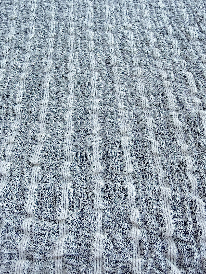 Tissu en coton froissé extensible neutre, surface texturée, coton tissé à la main blanc cassé, coton beige biologique semi-transparent et non blanchi.