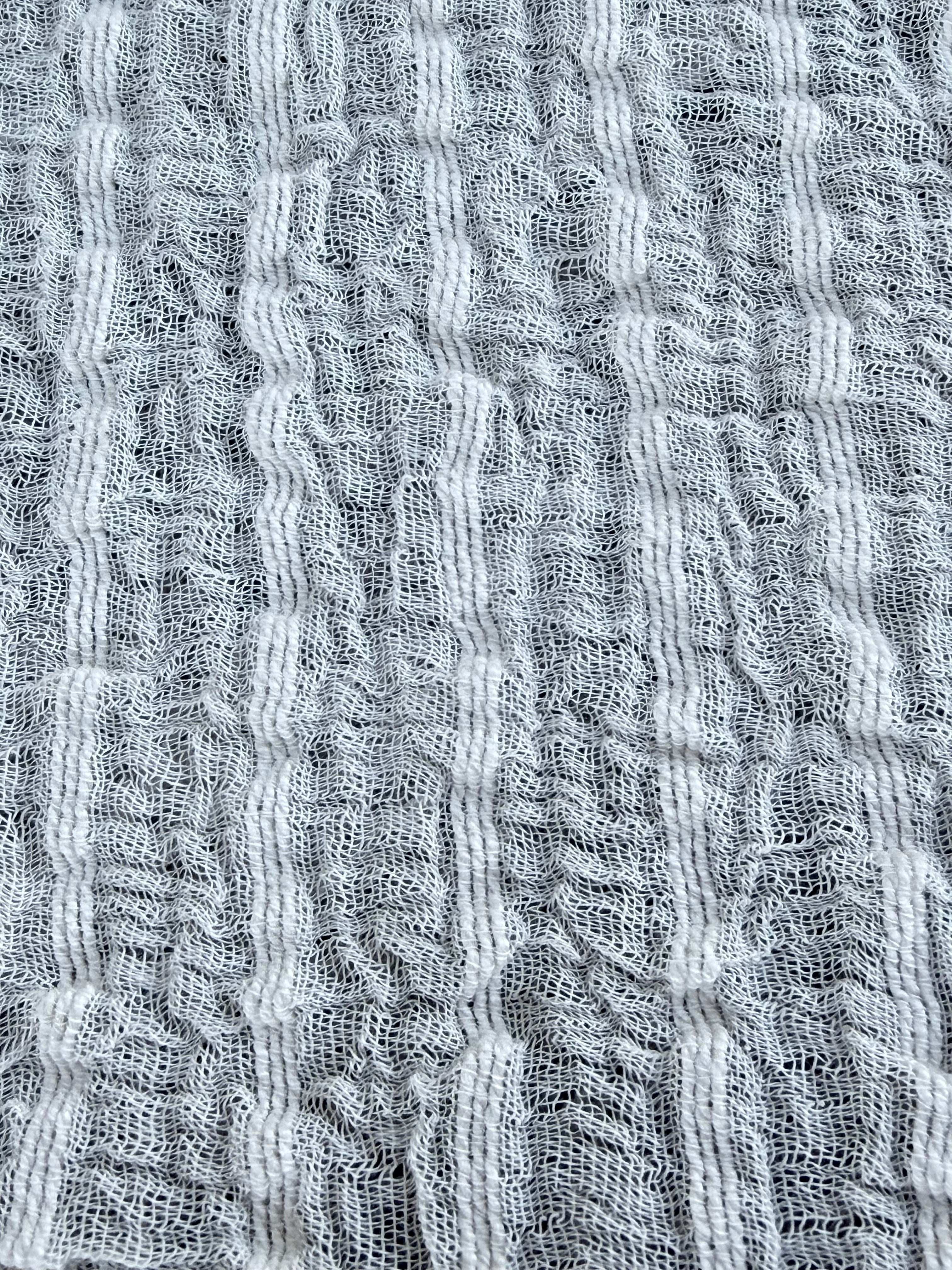 Tissu en coton froissé extensible neutre, surface texturée, coton tissé à la main blanc cassé, coton beige biologique semi-transparent et non blanchi.