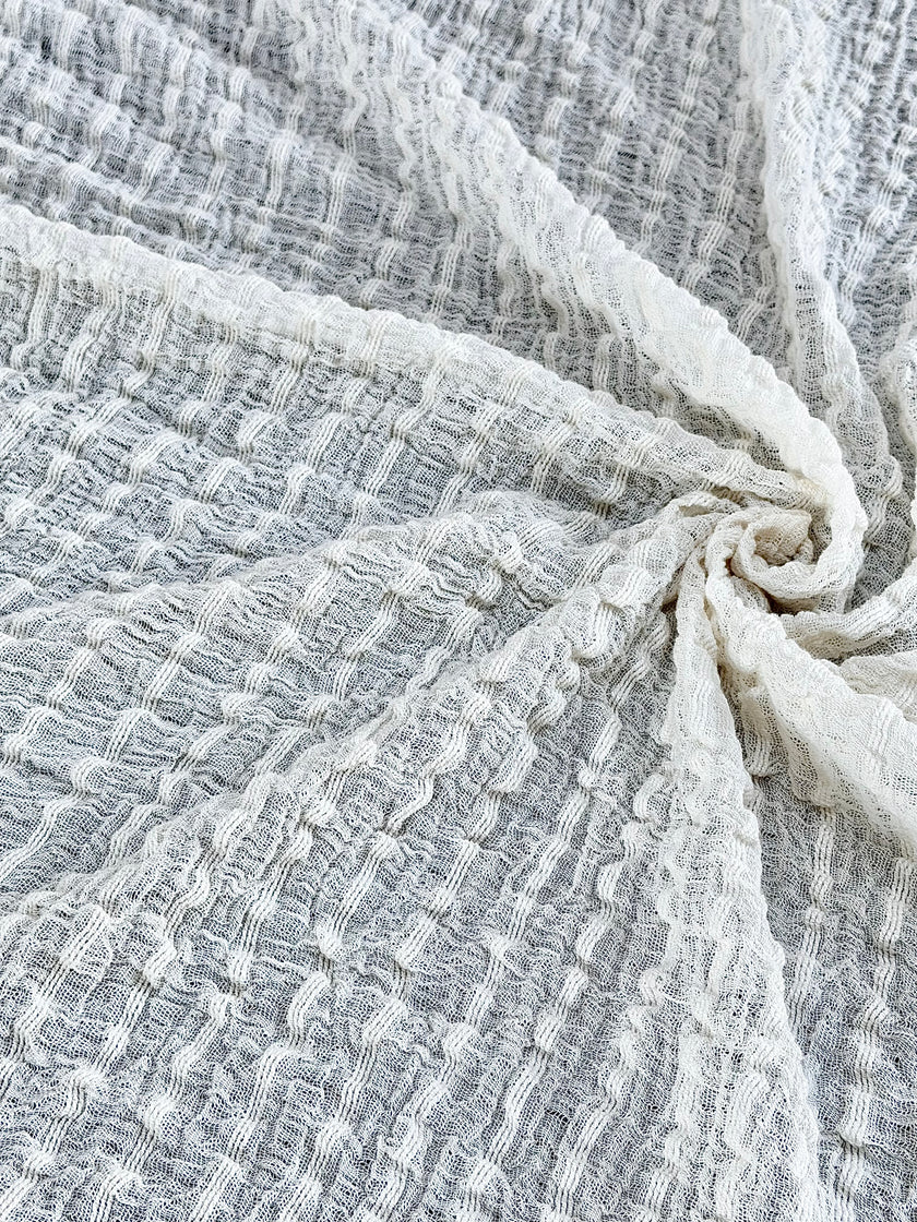 Tissu en coton froissé extensible neutre, surface texturée, coton tissé à la main blanc cassé, coton beige biologique semi-transparent et non blanchi.