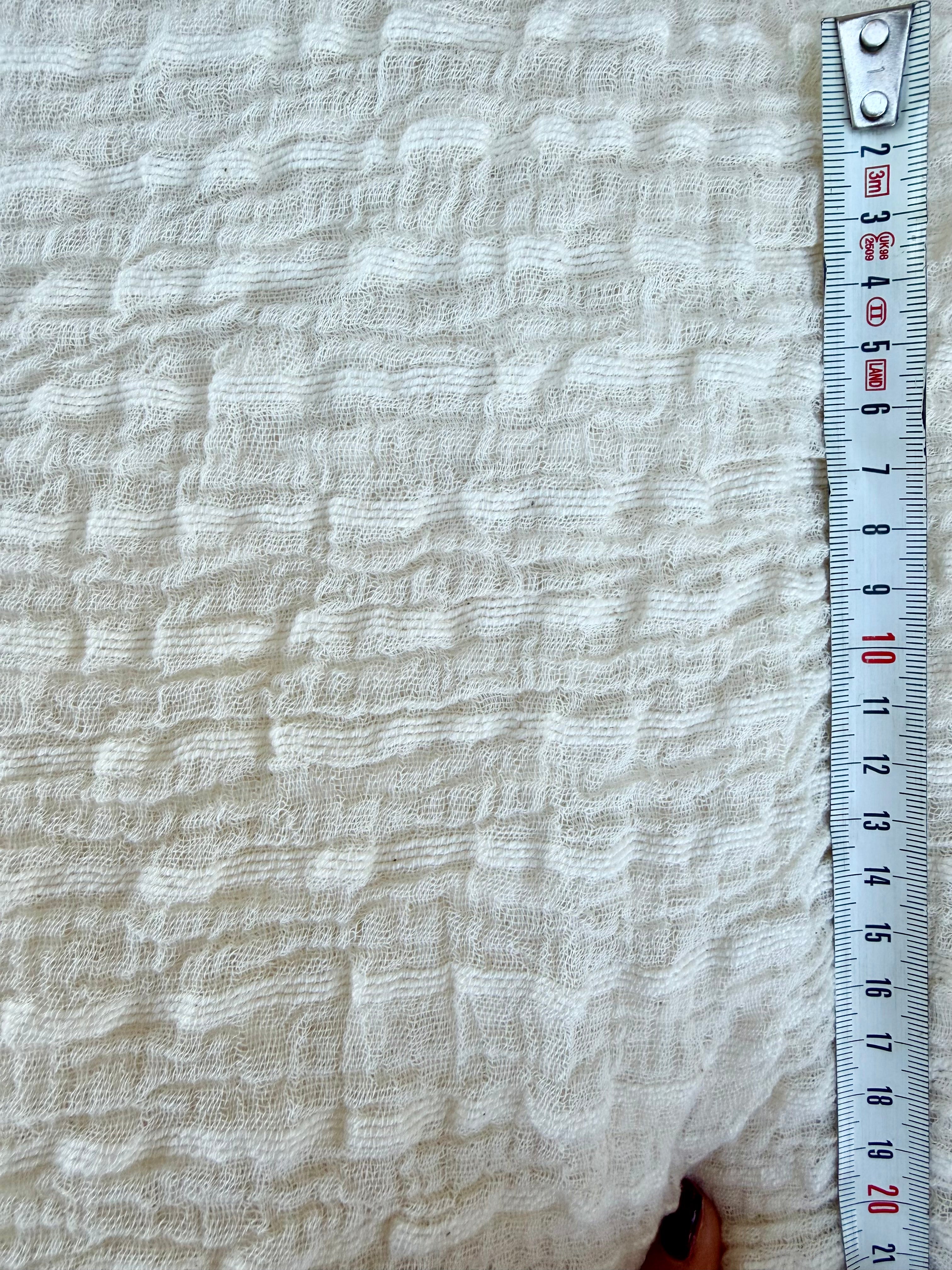 Tissu en coton froissé extensible neutre, surface texturée, coton tissé à la main blanc cassé, coton beige biologique semi-transparent et non blanchi.