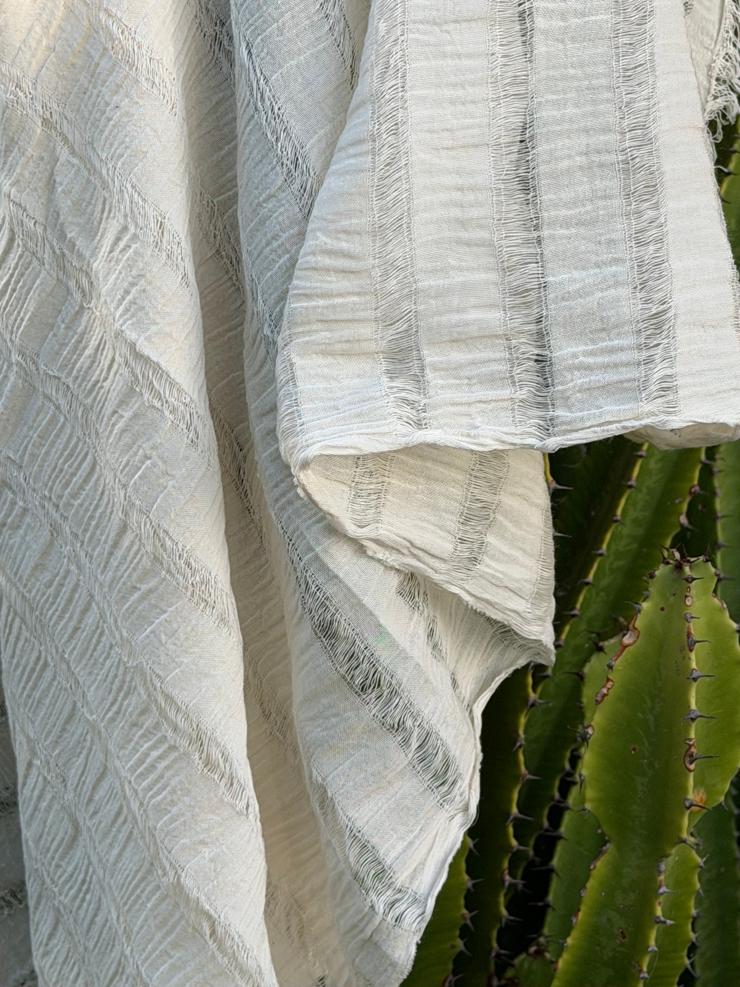 Tissu en coton froissé extensible neutre, surface texturée, coton tissé à la main blanc cassé, coton beige biologique semi-transparent et non blanchi.