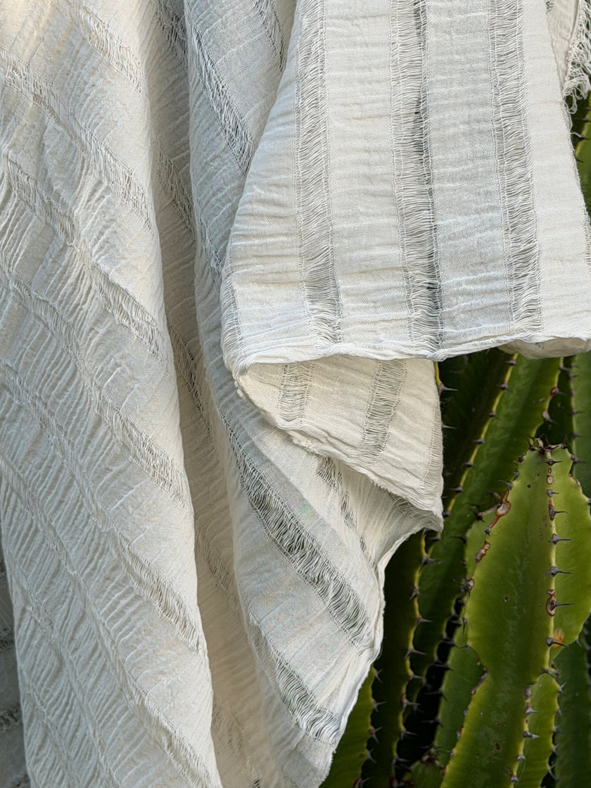 Tissu en coton froissé extensible neutre, surface texturée, coton tissé à la main blanc cassé, coton beige biologique semi-transparent et non blanchi.