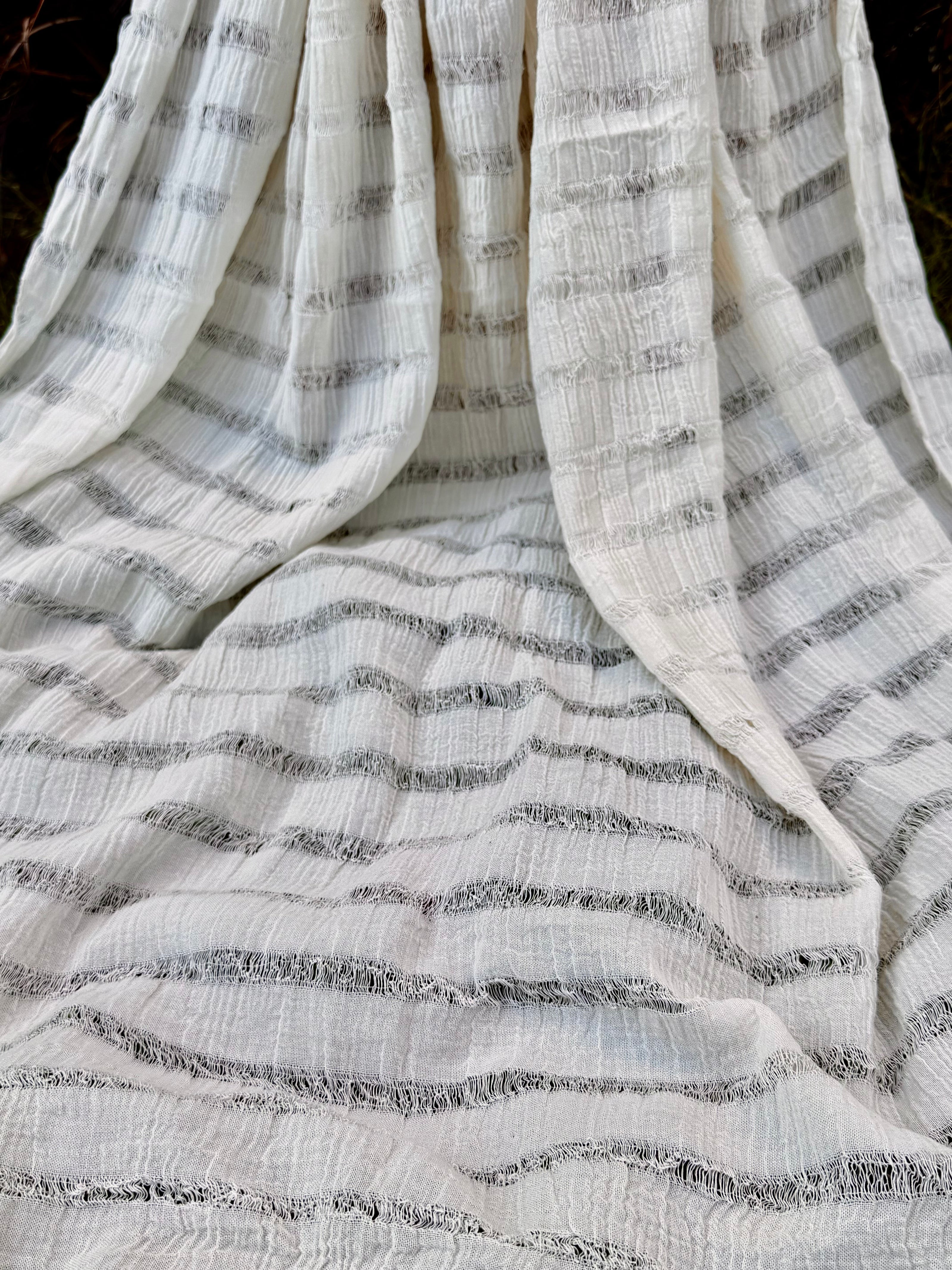 Tissu en coton froissé extensible neutre, surface texturée, coton tissé à la main blanc cassé, coton beige biologique semi-transparent et non blanchi.