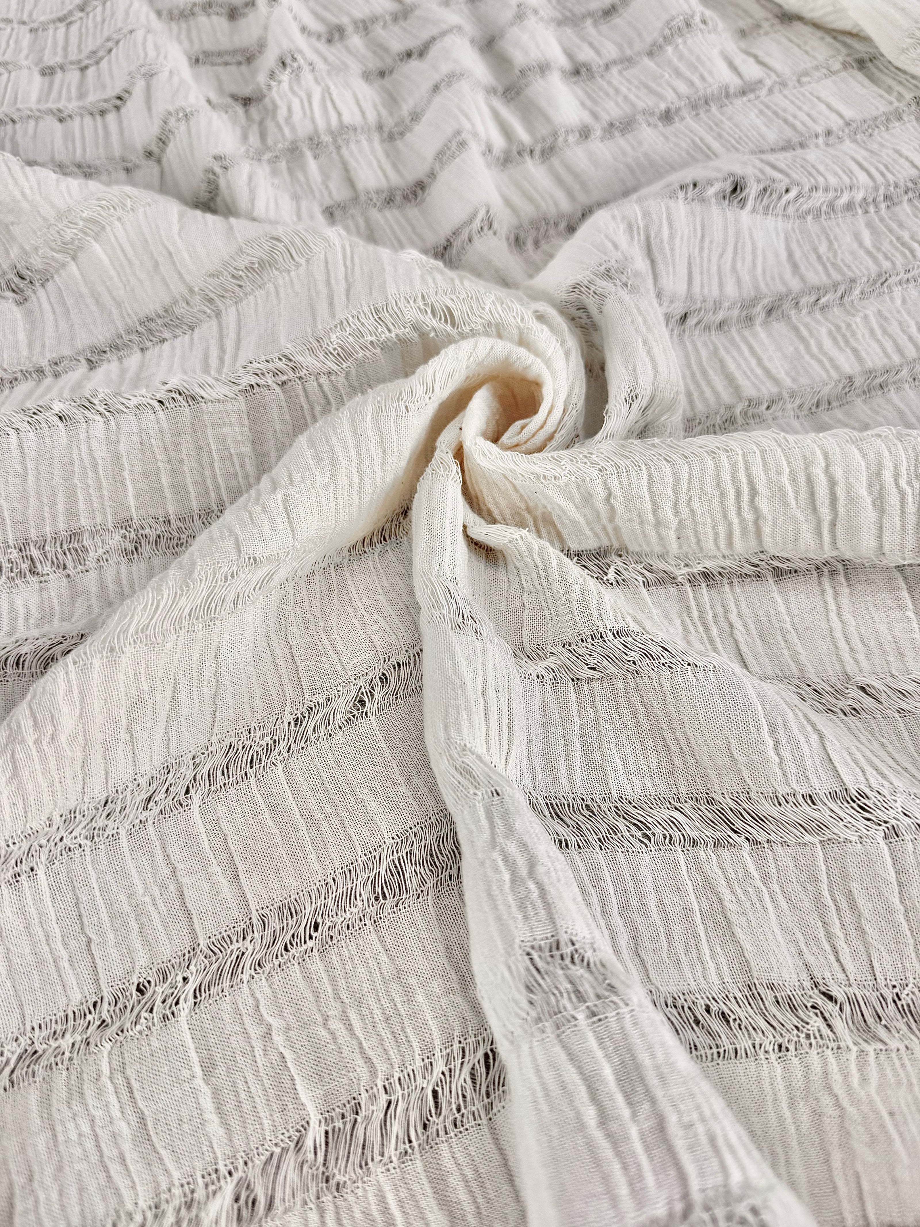 Tissu en coton froissé extensible neutre, surface texturée, coton tissé à la main blanc cassé, coton beige biologique semi-transparent et non blanchi.