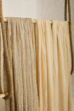 Tissu en coton froissé extensible neutre, surface texturée, coton tissé à la main blanc cassé, coton beige biologique semi-transparent et non blanchi.