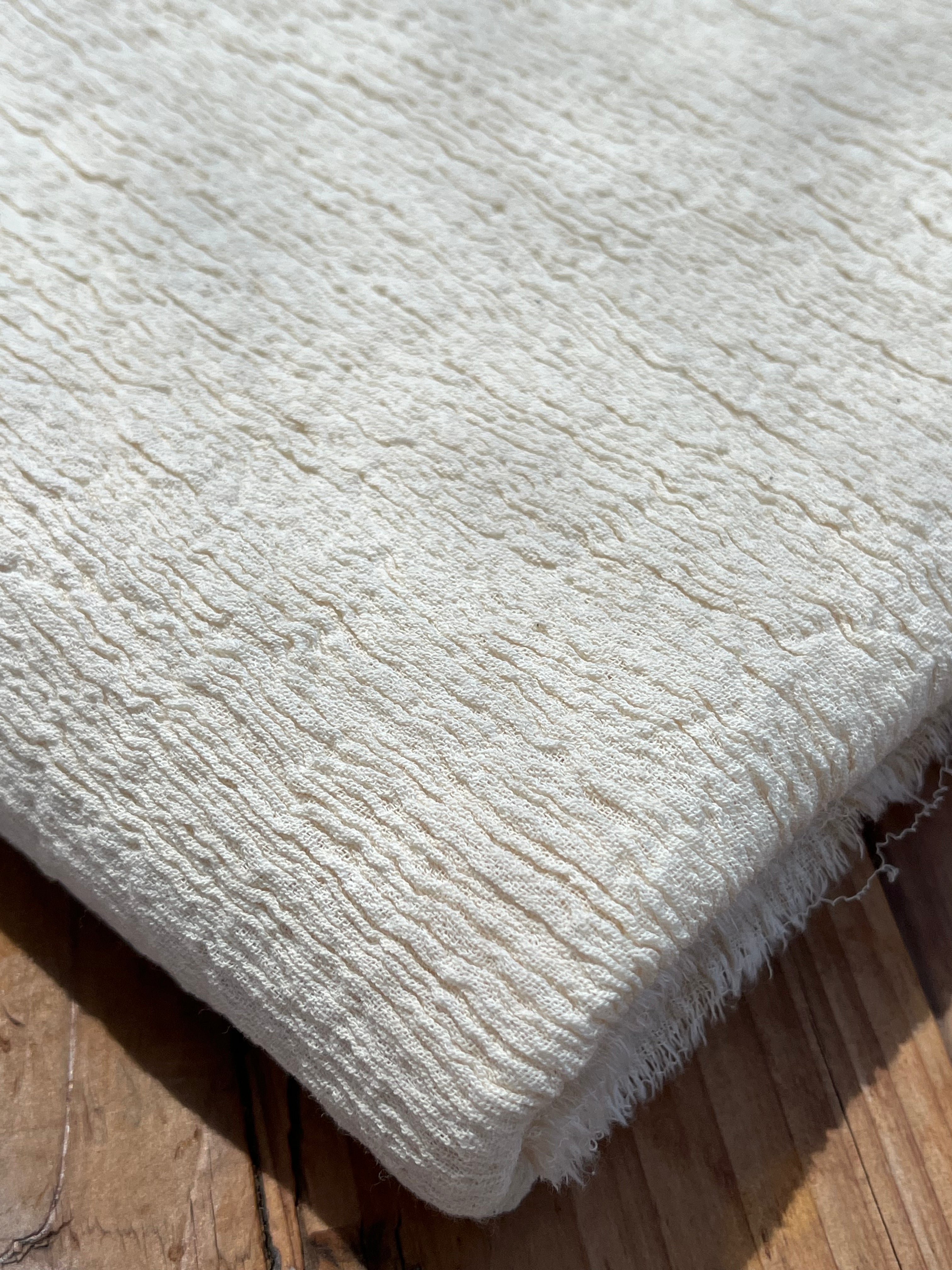 Tissu en coton froissé extensible neutre, surface texturée, coton tissé à la main blanc cassé, coton beige biologique semi-transparent et non blanchi.